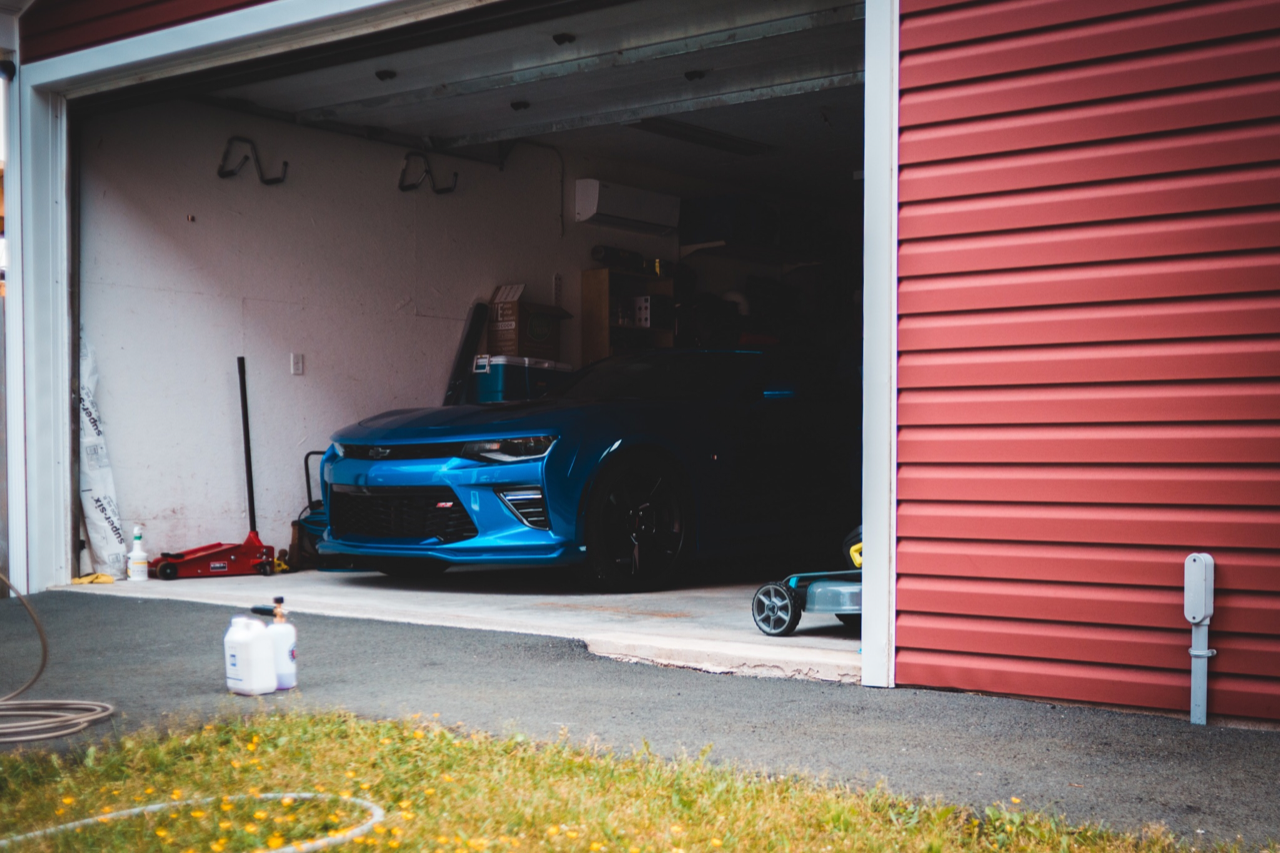 Car in a garage with red garage door visible