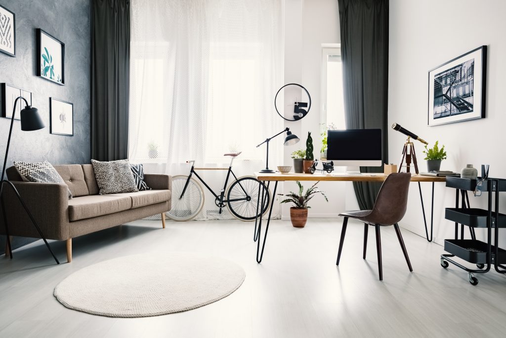 Modern home office interior with a big window, sofa, and desk are expected to be be home renovation trends for Toronto in 2022